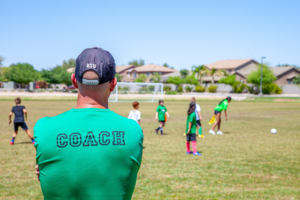 A good soccer coach observing players while using the Play-Practice-Play philosophy