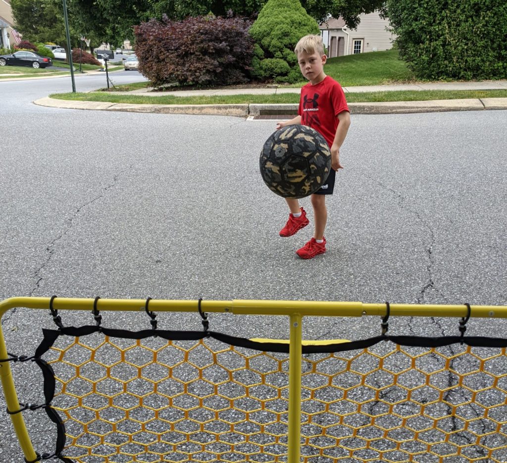 Youth player shooting at a Podiumax Portable Soccer Rebounder