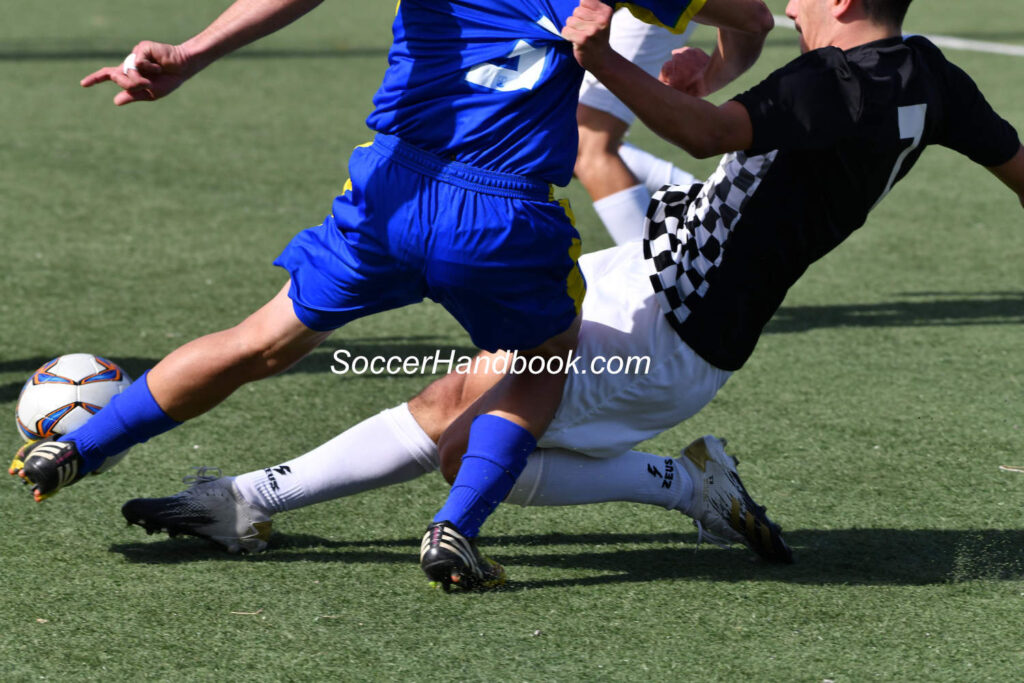 Soccer defender fouls opponent when slide tackling
