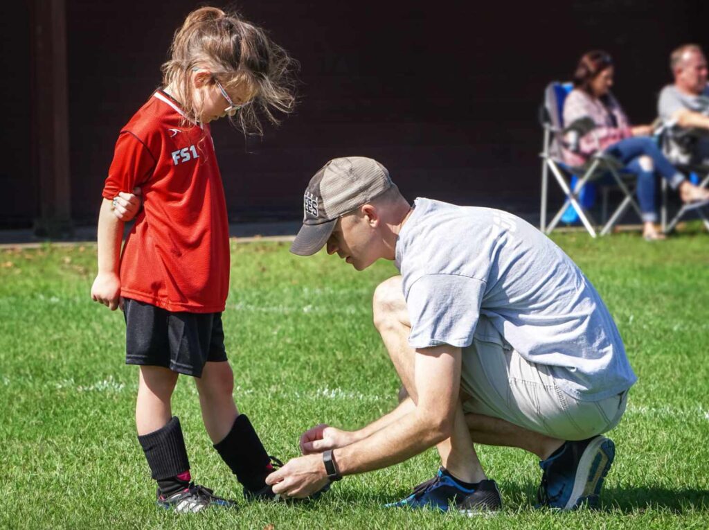 youth soccer coaching tying a shoe