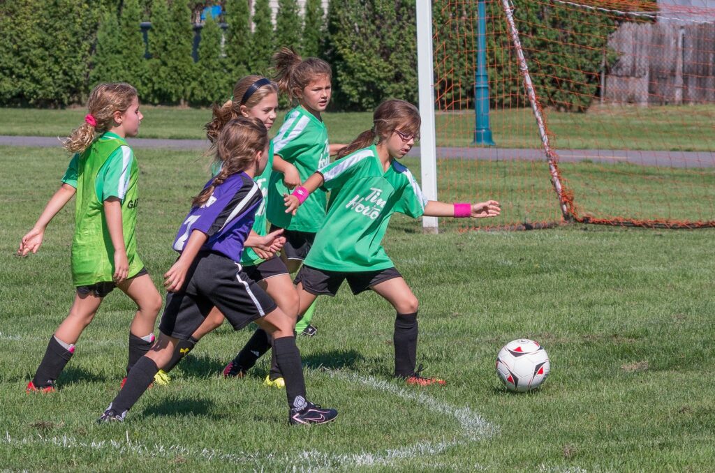 youth girl soccer player turning to shoot on goal in a game