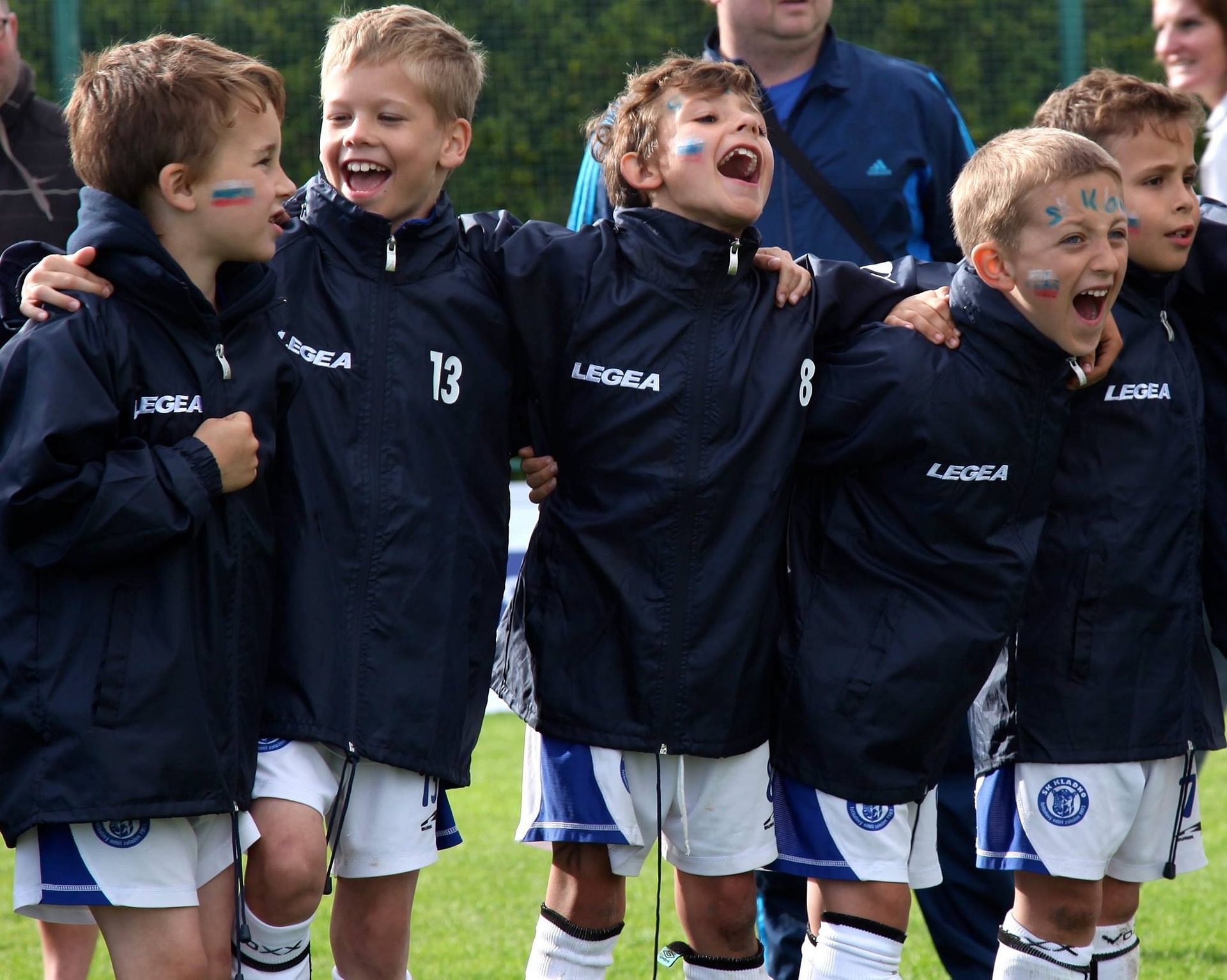 Youth soccer team standing in a line smiling and cheering.